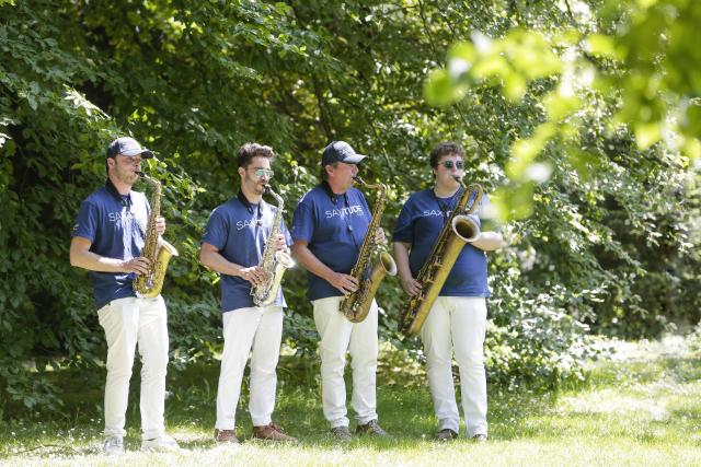 4 saxophonistes debout dans un jardin
