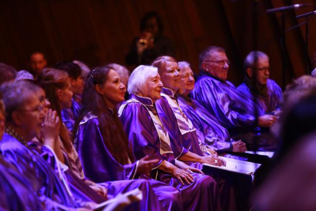 Des personnes âgées en robe violette chantant sur scène