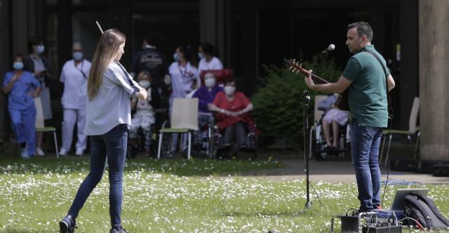 Deux musiciens jouant en extérieur devant des résidents d'une maison de retraite