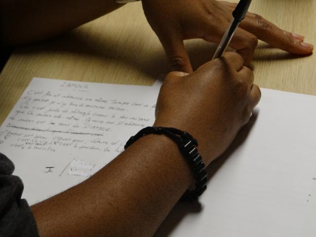 Une personne écrivant sur une feuille un texte sur l'amour