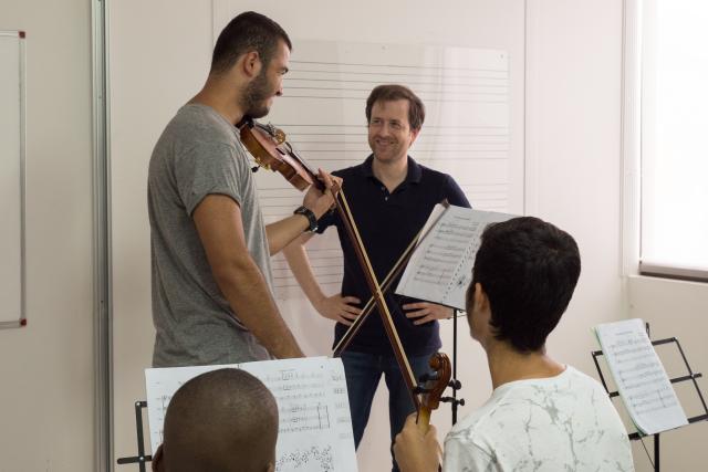 Enseignant apprenant le violon à un réfugier