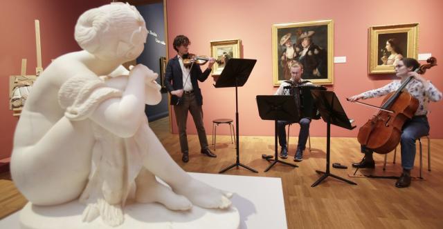 Trio d'artistes jouant du violon, de l'accordéon et de la contre basse dans un musée