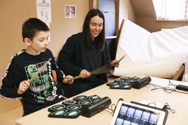 Deux adolescents jouant sur une batterie électrique reliée à un ordinateur