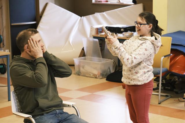 Une jeune fille jouant d'un instruement de percussion, debout à côté d'un homme assis