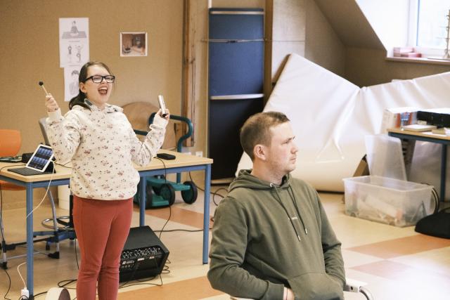 Une jeune fille jouant d'un instruement de percussion, debout derrière d'un homme assis