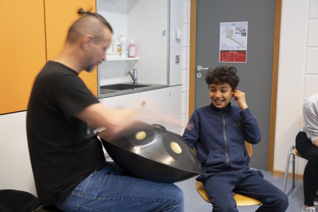 Un artiste jouant du handpan et un jeune garçon jouant avec lui sur le même instrument