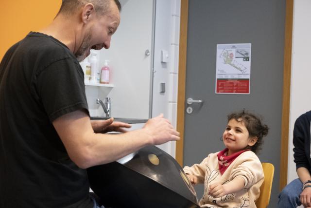 Un artiste jouant du handpan et une jeune fille jouant avec lui sur le même instrument