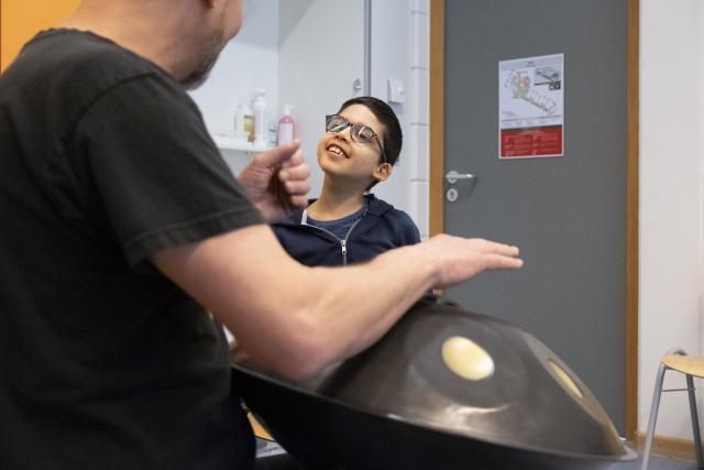 Un artiste jouant du handpan et un jeune garçon jouant avec lui sur le même instrument