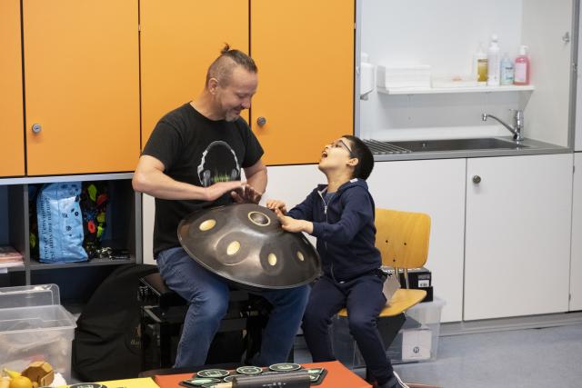 Un artiste jouant du handpan et un jeune garçon jouant avec lui sur le même instrument