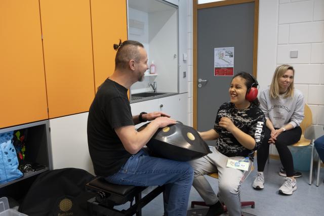 Un artiste jouant du handpan et un enfant portant un casque jouant avec lui sur le même instrument