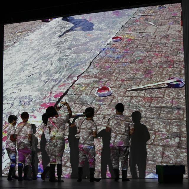 Des enfants sur scène et derrière une projection colorée