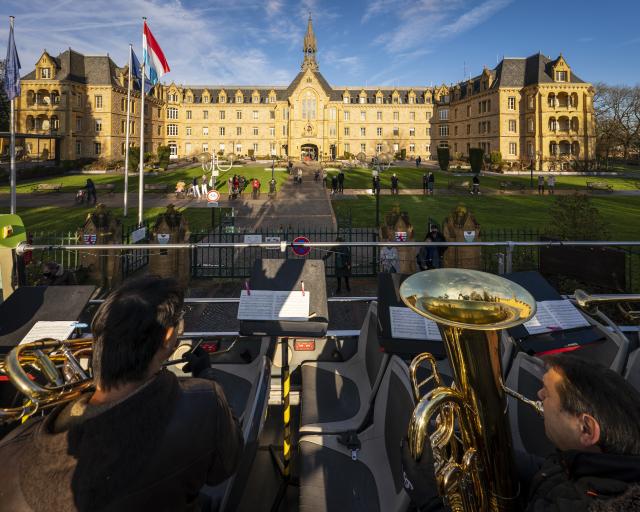 Des musiciens sur l'étage ouvert d'un bus devant la Fondation Pescatore