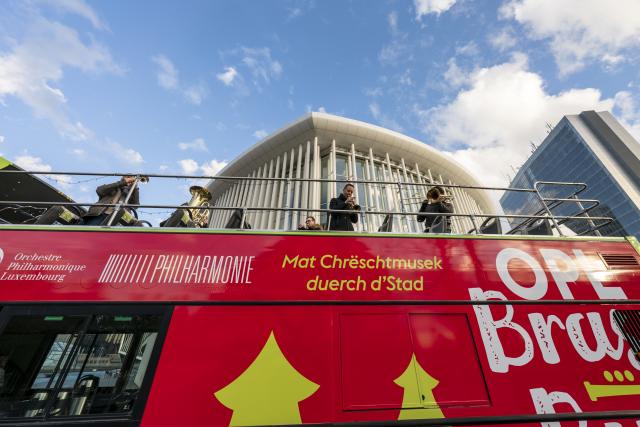 Des musiciens sur l'étage ouvert d'un bus devant la Philharmonie Luxembourg