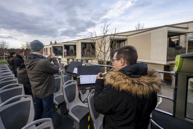 Des musiciens sur l'étage ouvert d'un bus devant des habitations