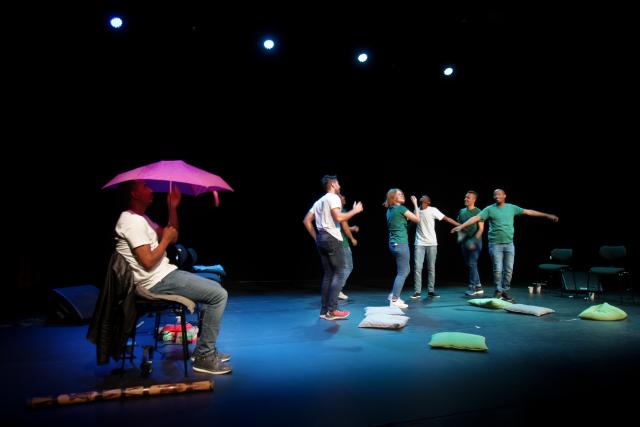 Des personnes habillées en vert faisant du théâtre sur scène