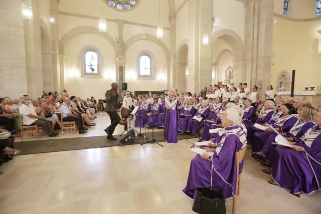 Une large chorale de personnes en robe violette chantant dans une église
