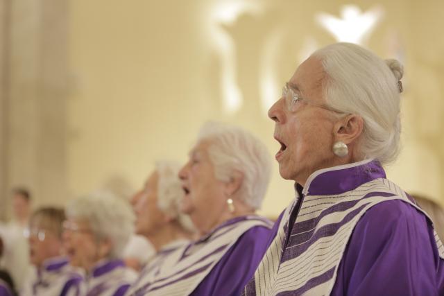 Des personnes âgées en robe violette chantant ensemble