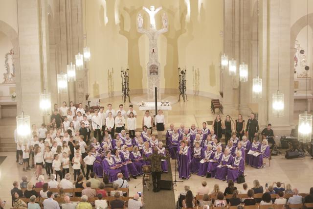 Une large chorale de personnes en robe violette chantant dans une église