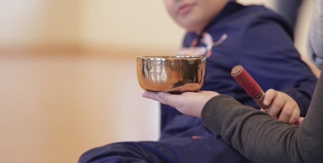 Un enfant jouant d'un instrument de percussion qui ressemble à un bol