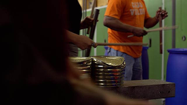 Des personnes tappant sur des fûts métalliques avec des baguettes