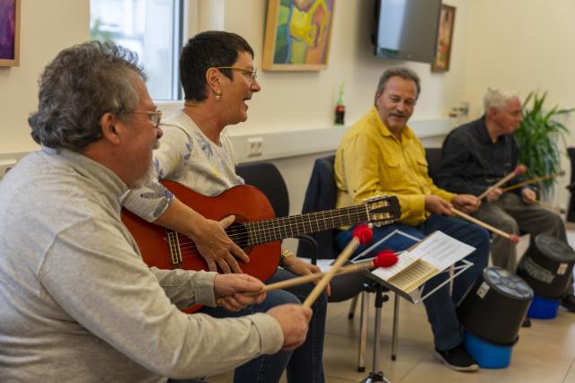 Une guitariste chantant avec des personnes tappant sur des sceaux en plastique avec des baguettes