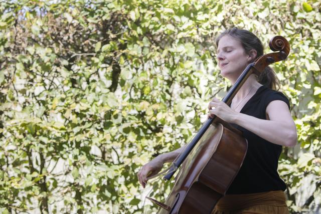 Une femme jouant du violoncelle dans un jardin en fermant les yeux