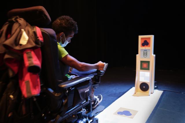 Un jeune homme en fauteil roulant devant une installation musicale en bois