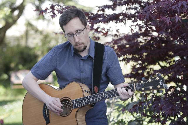 Un homme jouant de la guitarre dans un jardin