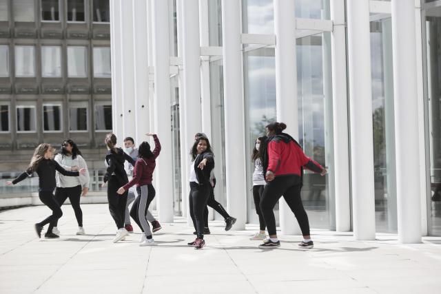 Des adolescents dansant sur le parvis d'un bâtiment 