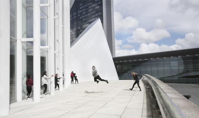 Des adolescents dansant sur le parvis d'un bâtiment 