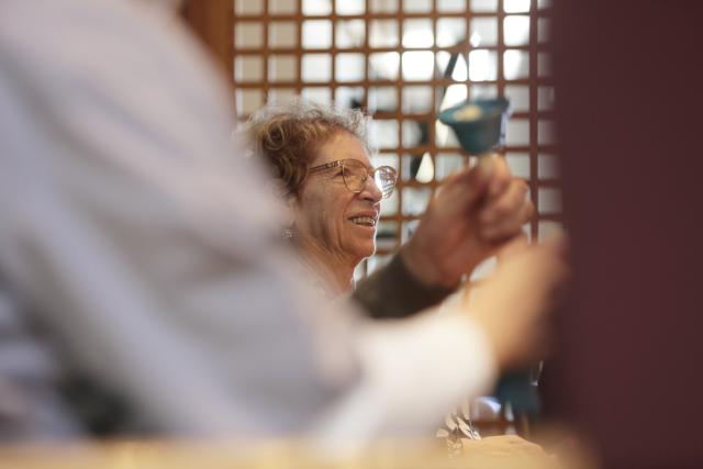 Une personne âgée secouant une clochette en souriant