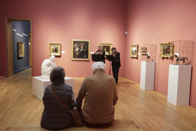 Deux personnes assises écoutant deux musiciens jouant dans un musée