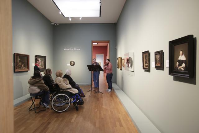 Deux violonistes jouant devant des personnes en fauteuil roulant dans un musée