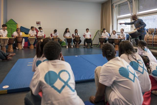 Des enfants rassemblés autour d'un percussioniste