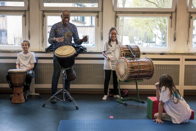 Un percussioniste et des enfants jouant du djémbé et du Dum-Dum