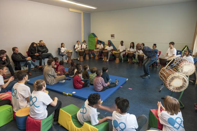 Des enfants rassemblés autour d'un percussioniste