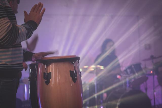 Des personnes jouant d'un instrument de percussions éclairé en contre-jour