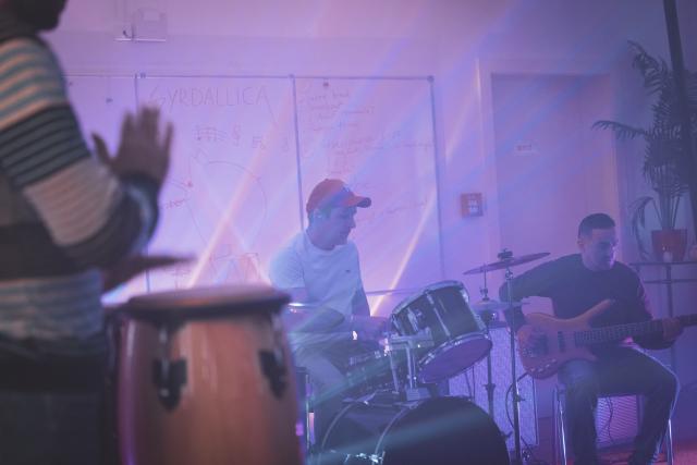 Un homme jouant de la batterie, un homme jouant de la guitarre et une personne jouant des percussions