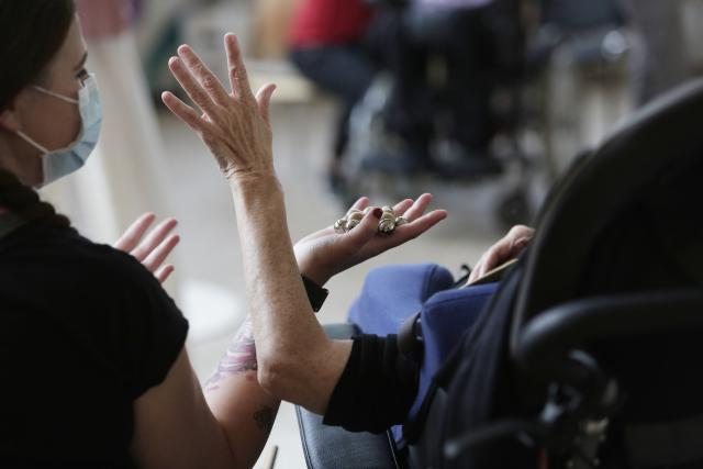 Deux femmes, dont l'une en fauteuil roulant levant un bras