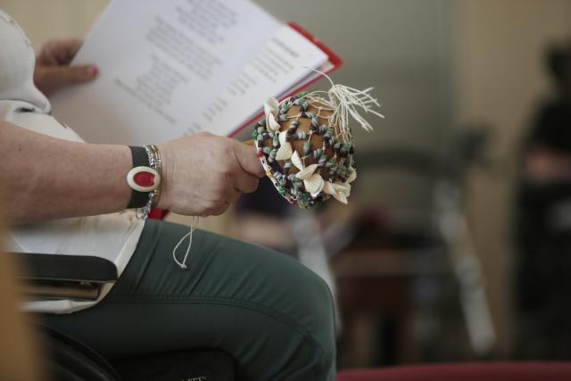 Une femme tenant des textes de chansons et jouant d'un petit instrument de percussion