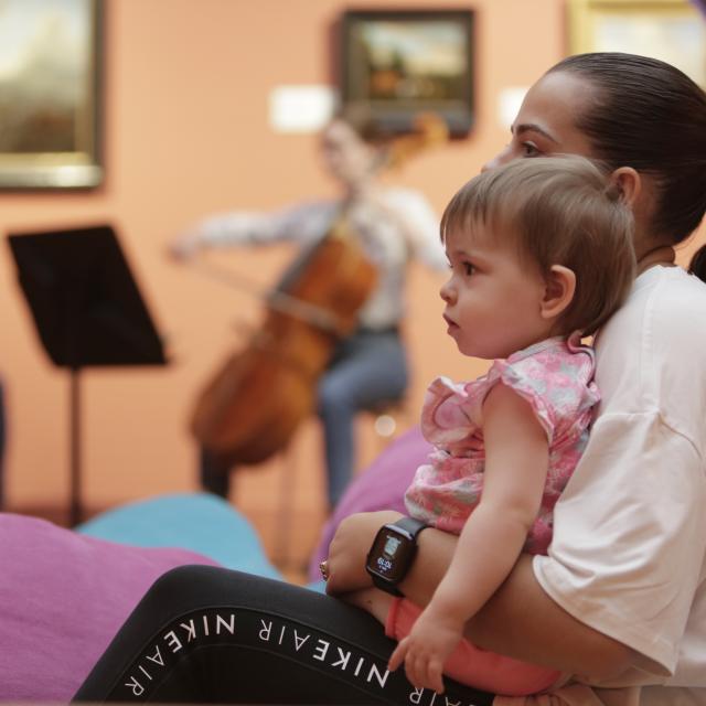 Un bébé sur les genoux d'une femme écoutant de la musique dans un musée