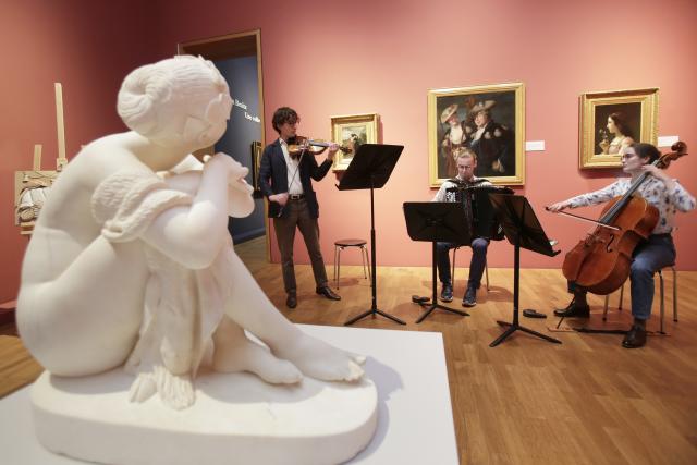 Des musiciens dans un musée avec une statue au premier plan