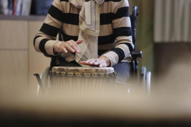 Un femme dans un fauteil roulant jouan du djembé