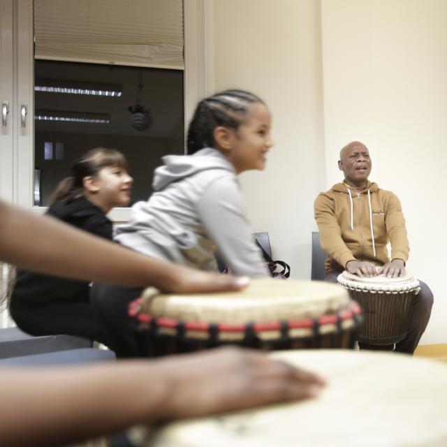 Des enfants jouant du djembé et souriant