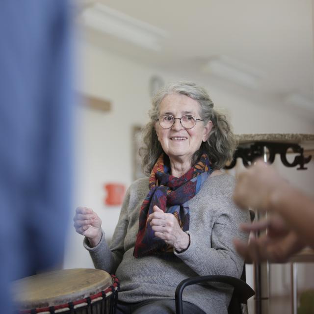 Une femme jouant du djembé et souriant