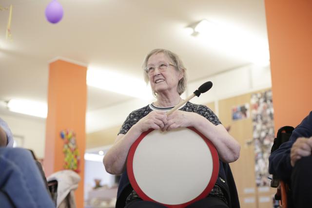 Une femme tenant un tambour et souriant