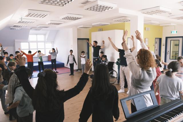 Un large groupe d'enfants en rond levant les bras