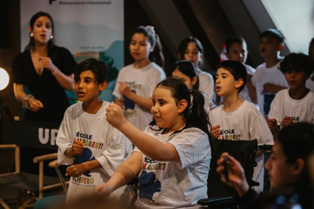 Un groupe d'enfants portant le même t-shirt blanc sur scène 