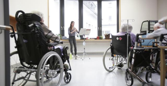 Des personnes en fauteuil roulant écoutant un concert dans un hôpital