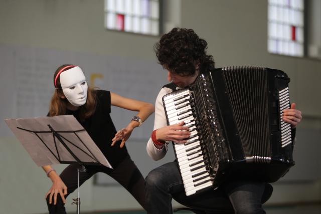 Une jeune fille masquée dansant à côté d'une accordéoniste